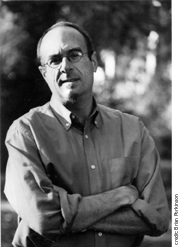 this is a photo of the author, Brian Bouldrey, in shirt sleeves, with his arms crossed. He wears glasses.