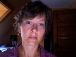 this is a photo of author Laurie Hovell McMillin. She has short hair an appears to be at work in a writing space.